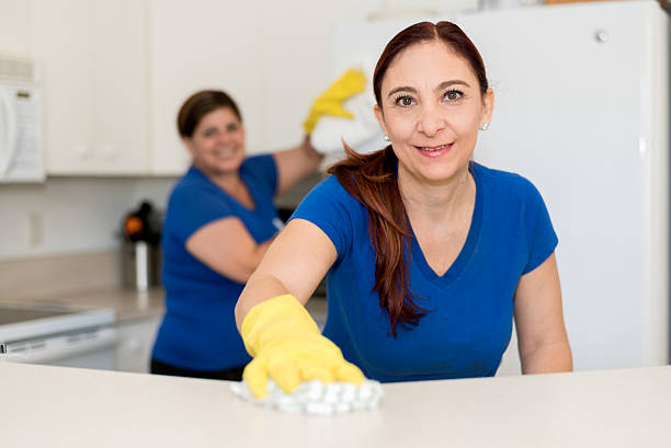 Smiling cleaning lady in yellow rubber gloves during work