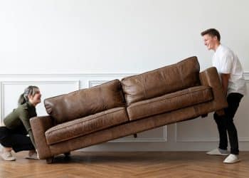 A person lifting a couch Description automatically generated