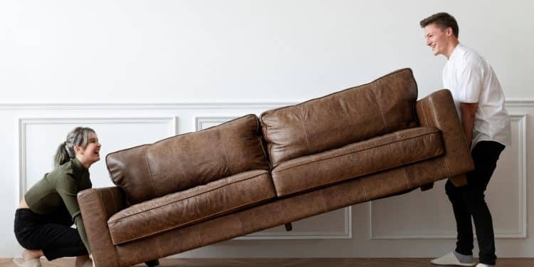 A person lifting a couch Description automatically generated