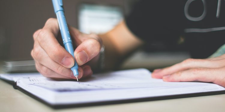 a man writing on a notebook