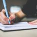 a man writing on a notebook