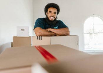 Recent college graduate packing moving boxes in a New York apartment
