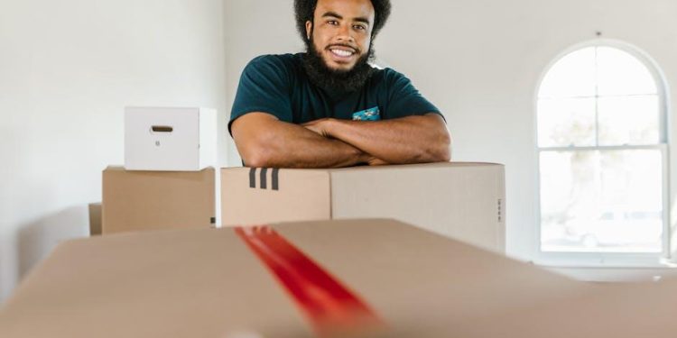 Recent college graduate packing moving boxes in a New York apartment