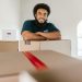 Recent college graduate packing moving boxes in a New York apartment