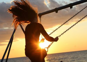 woman riding on swing during sunset