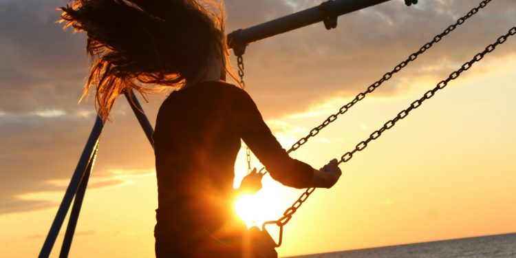 woman riding on swing during sunset